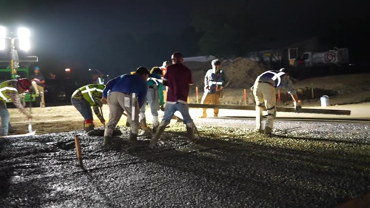 Concrete crew placing and leveling a slab at night